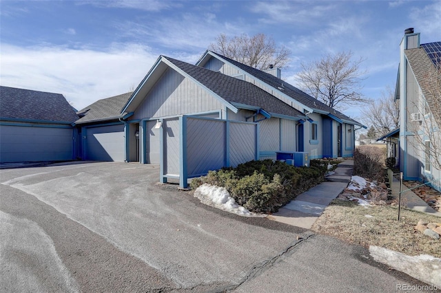 view of home's exterior with a garage, aphalt driveway, and a shingled roof