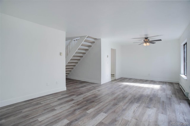 interior space featuring baseboards, ceiling fan, stairway, and light wood finished floors