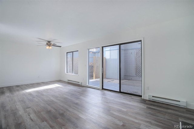 spare room featuring a baseboard radiator, baseboards, and wood finished floors