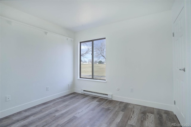 unfurnished room with baseboards, baseboard heating, and light wood-style floors