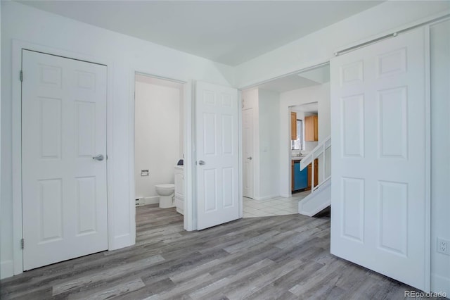 unfurnished bedroom featuring baseboards, light wood-style flooring, and ensuite bath