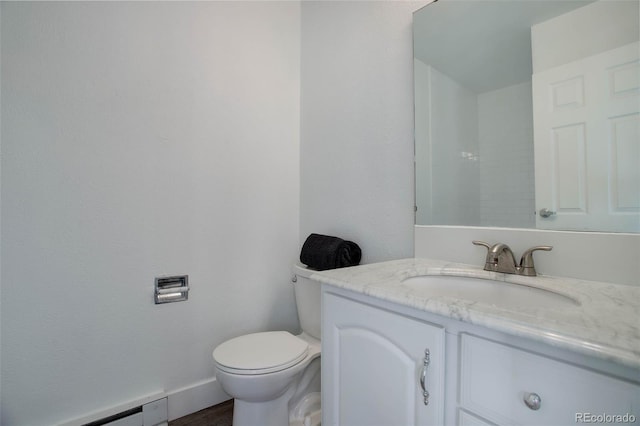 bathroom with toilet, baseboards, baseboard heating, and vanity