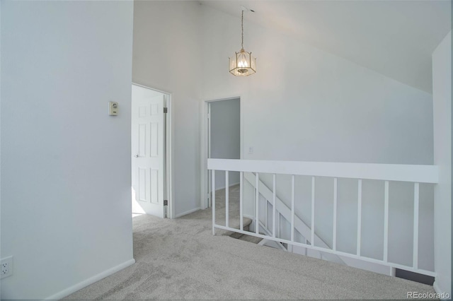 hallway featuring baseboards, high vaulted ceiling, and light colored carpet