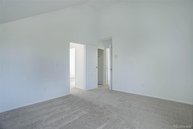 spare room featuring high vaulted ceiling and light colored carpet