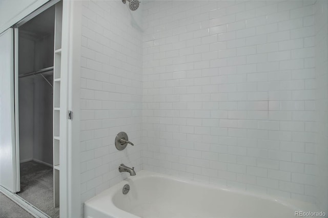 bathroom with bathtub / shower combination and a walk in closet