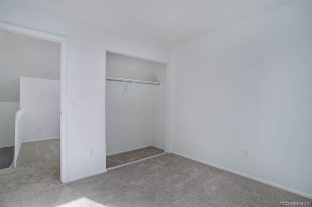 unfurnished bedroom featuring a closet and light colored carpet