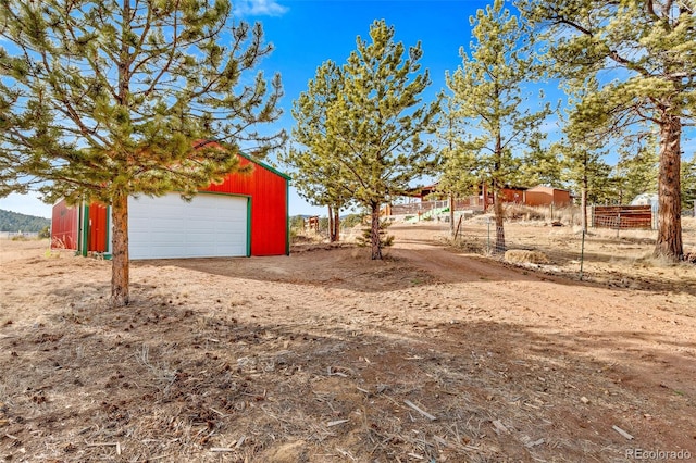 view of yard featuring a garage, an outdoor structure, and fence