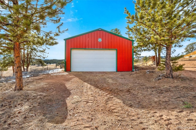 detached garage featuring dirt driveway and a rural view