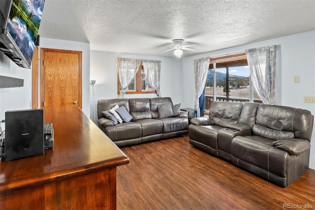 living room with ceiling fan, a textured ceiling, and dark wood finished floors