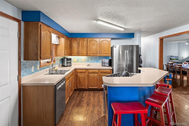 kitchen featuring a breakfast bar area, stainless steel appliances, a sink, light countertops, and a center island