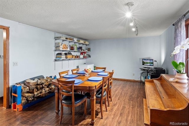 dining space featuring track lighting, a textured ceiling, baseboards, and wood finished floors