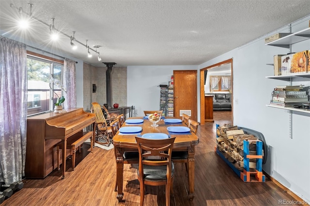 dining space with a wood stove, a textured ceiling, and wood finished floors