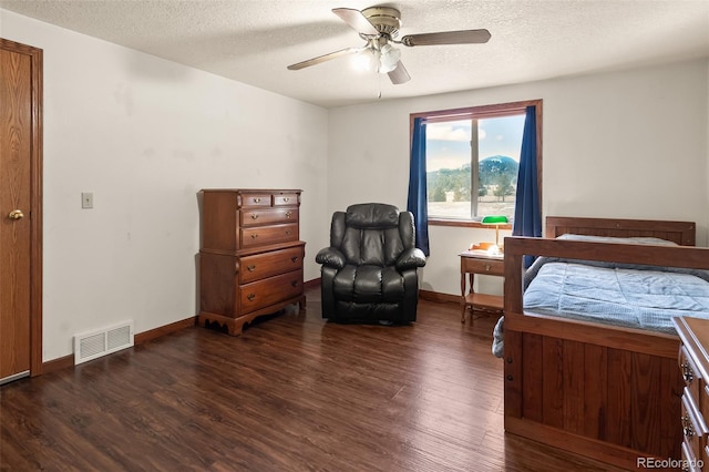 bedroom featuring dark wood-style floors, baseboards, visible vents, and a textured ceiling