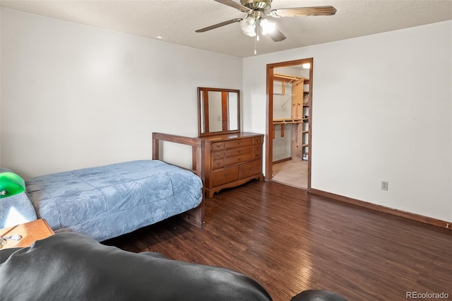 bedroom with a textured ceiling, dark wood finished floors, a ceiling fan, and baseboards