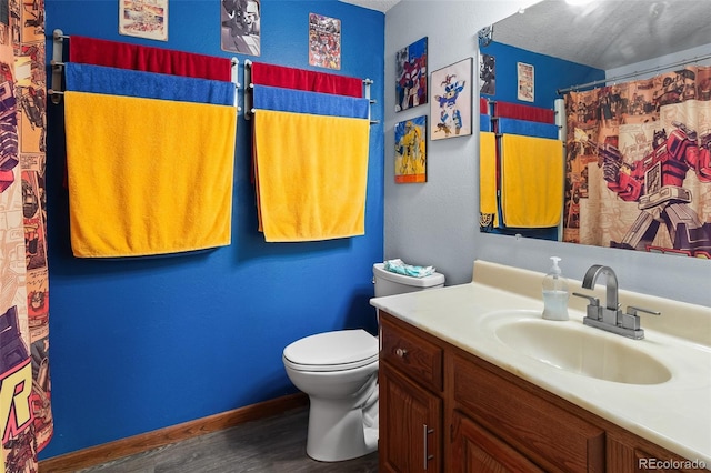 bathroom featuring baseboards, toilet, wood finished floors, curtained shower, and vanity