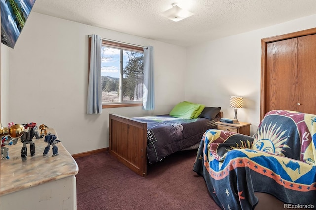 bedroom featuring dark carpet, a textured ceiling, and baseboards