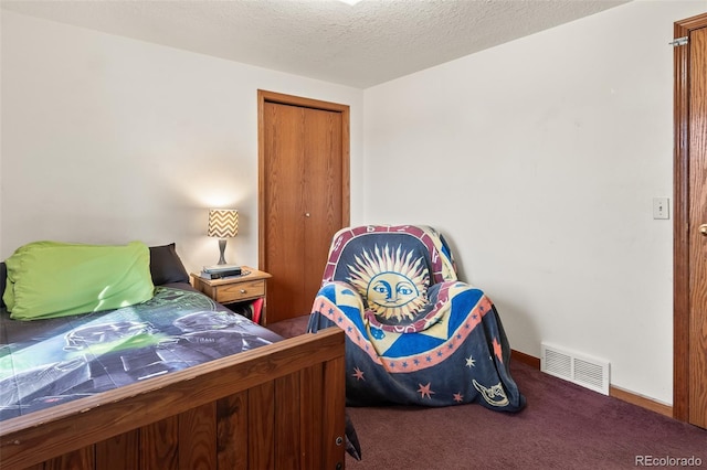 bedroom with a textured ceiling, visible vents, baseboards, a closet, and carpet