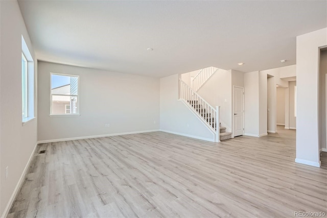 unfurnished living room with stairs, light wood-style flooring, baseboards, and recessed lighting