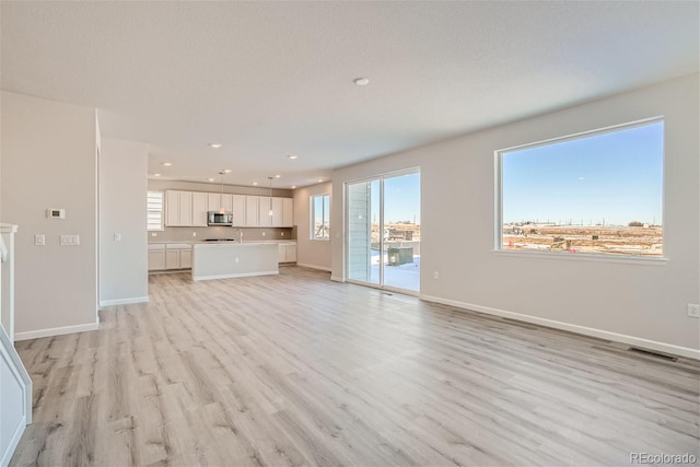 unfurnished living room featuring light wood-style floors, recessed lighting, and baseboards