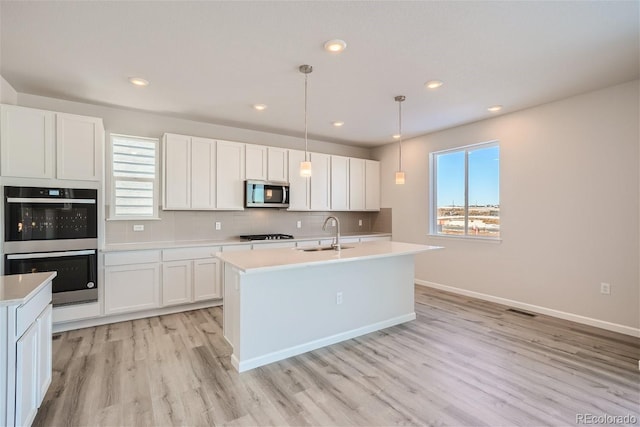 kitchen with stainless steel appliances, a sink, plenty of natural light, light countertops, and recessed lighting