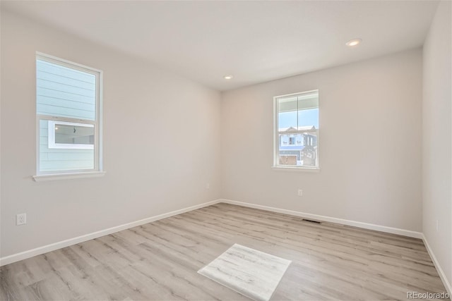 empty room featuring light wood finished floors, baseboards, and recessed lighting