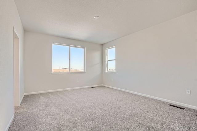 empty room featuring carpet flooring, baseboards, and a textured ceiling