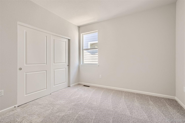 unfurnished bedroom featuring carpet flooring, baseboards, and a closet