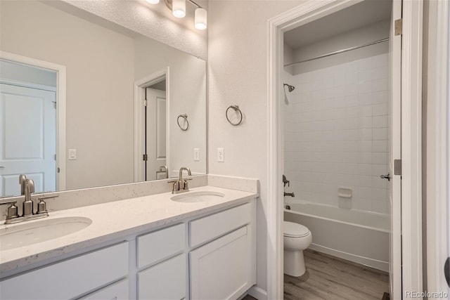 full bath featuring toilet, wood finished floors, double vanity, and bathtub / shower combination