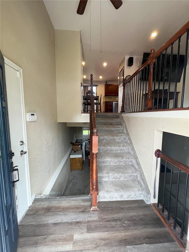 stairway with hardwood / wood-style flooring and ceiling fan