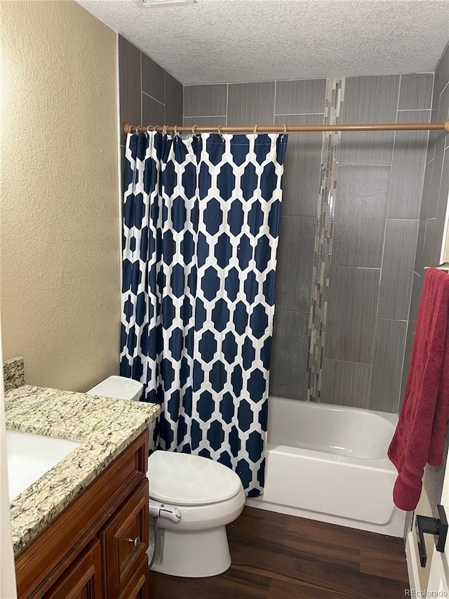 full bathroom featuring vanity, a textured ceiling, toilet, hardwood / wood-style floors, and shower / tub combo with curtain