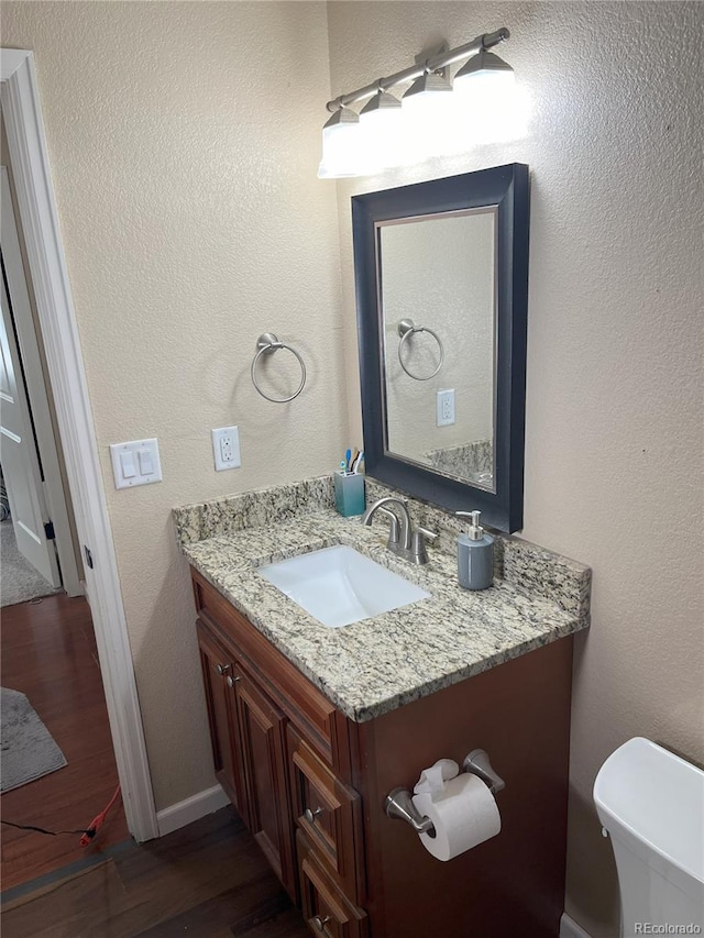 bathroom featuring toilet, vanity, and hardwood / wood-style flooring