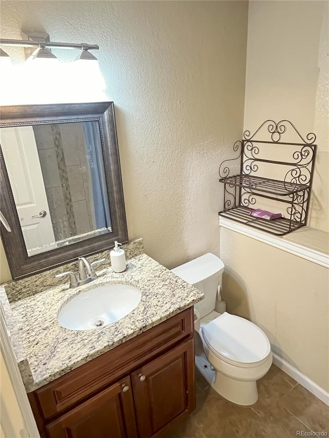 bathroom with toilet, vanity, and tile patterned floors