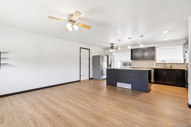 108 Olympus Cir, Lone Tree, CO 80124 - kitchen featuring stainless steel fridge, light wood-style floors, ceiling fan, a kitchen island, and decorative backsplash