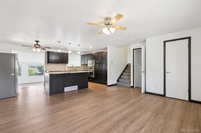 108 Olympus Cir, Lone Tree, CO 80124 - kitchen featuring stainless steel appliances, ceiling fan, light countertops, light wood-type flooring, and decorative backsplash