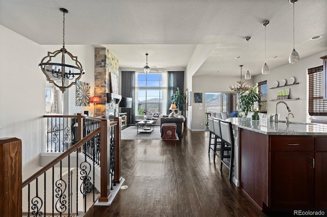 15290 W Baker Ave, Lakewood, CO 80228 - kitchen featuring a chandelier, dark wood finished floors, open floor plan, light stone counters, and a ceiling fan