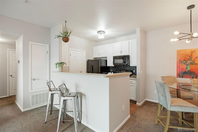 kitchen with pendant lighting, white cabinets, black appliances, and kitchen peninsula