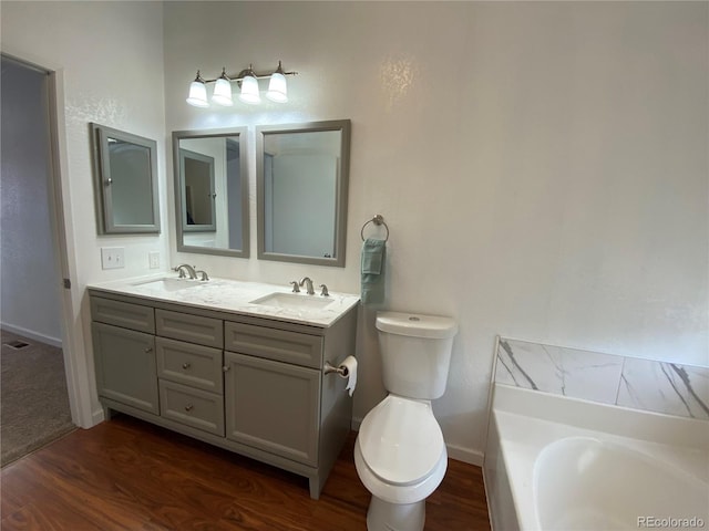 bathroom with wood-type flooring, vanity, toilet, and a washtub