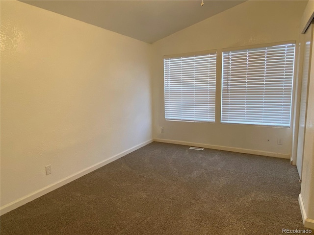 carpeted empty room featuring lofted ceiling