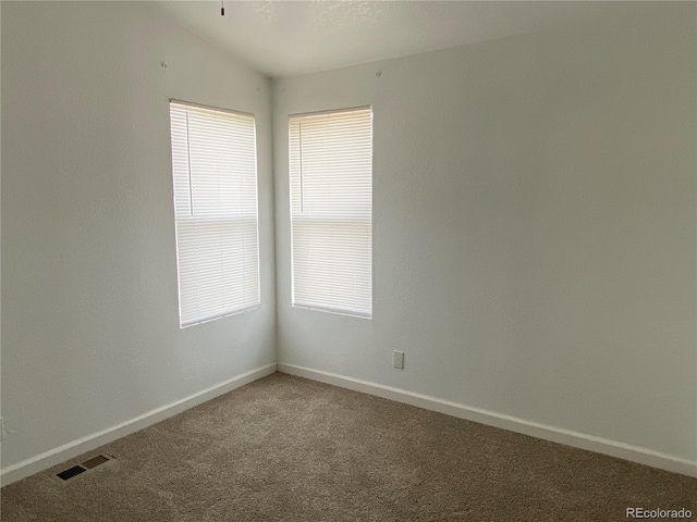 carpeted spare room with lofted ceiling and plenty of natural light