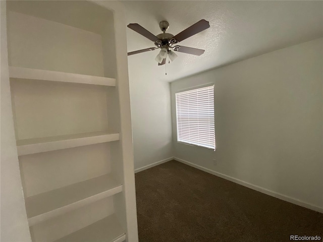 empty room with dark colored carpet, ceiling fan, and a textured ceiling