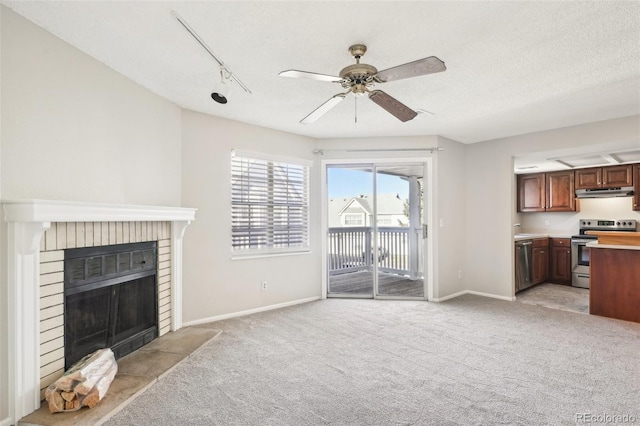 unfurnished living room with light carpet, ceiling fan, a brick fireplace, a textured ceiling, and rail lighting