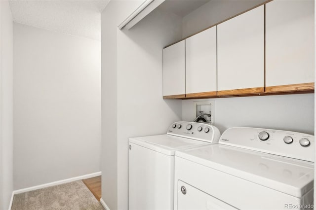 laundry area with light colored carpet, cabinets, a textured ceiling, and washing machine and clothes dryer