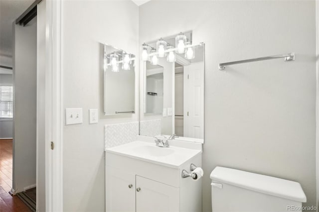 bathroom featuring toilet, vanity, and tasteful backsplash