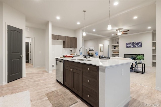 kitchen with dark brown cabinetry, sink, stainless steel dishwasher, and a center island with sink