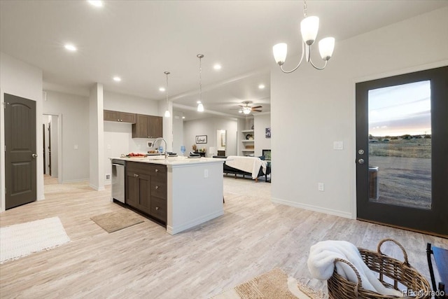 kitchen featuring stainless steel dishwasher, decorative light fixtures, a kitchen island with sink, and light hardwood / wood-style flooring