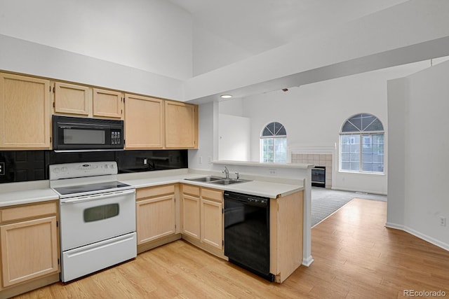 4883 W 68th Ave Unit 3, Westminster, CO 80030 - kitchen featuring black appliances, light brown cabinetry, a peninsula, tasteful backsplash, and high vaulted ceiling
