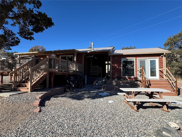 rear view of house with a wooden deck and a patio