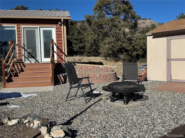 view of patio featuring a storage shed and an outdoor fire pit