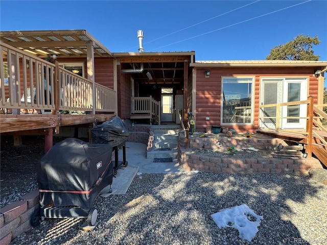 back of house with a wooden deck and a patio