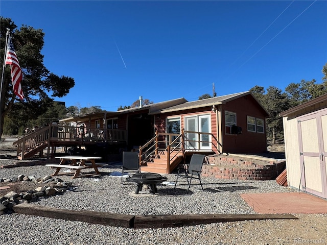 rear view of house with a deck and a storage unit